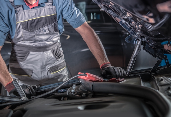 mechanic working on car alternator and battery