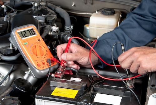 auto mechanic testing car battery voltage