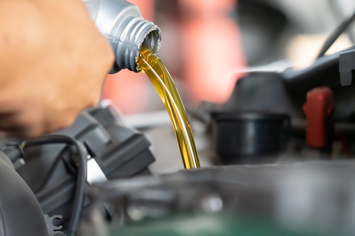 mechanic pouring oil into engine