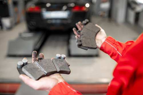 auto mechanic holding two brake pads