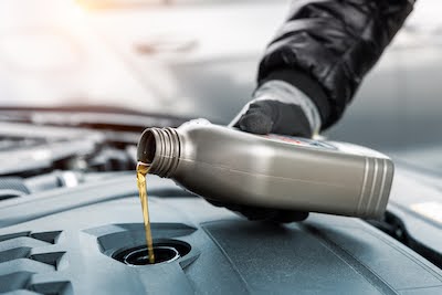 auto mechanic pouring motor oil into the car engine